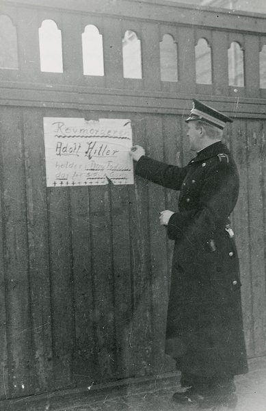 Betjent fjerner illegal plakat
