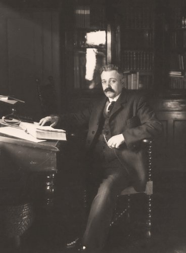 Portrætfoto af Thøger Larsen siddende ved bog
