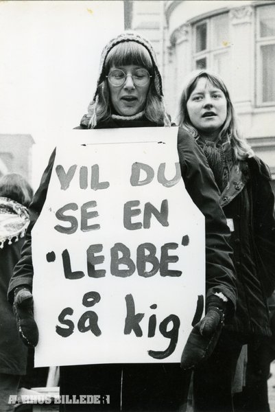 Kvinde holder skilt hvor der står "Vil du se en "lebbe" så kig!"